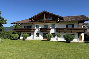 A two-story chalet with a sloped roof, wooden balconies, and a well-maintained lawn. - Holiday apartment with 1 bedroom (Schwangau)