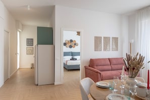 Ein modernes Wohnzimmer mit einer Couch, einem Esstisch und einem Bett im Hintergrund.