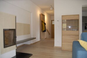 A hallway with a wooden bench, a coat rack with a yellow jacket, and a door leading to a kitchen area. - Holiday apartment with 1 bedroom (Breitenberg)