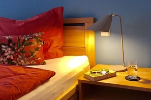 A bed with a wooden headboard, a nightstand with a lamp, and a glass of water. - Holiday apartment with 1 bedroom (Breitenberg)