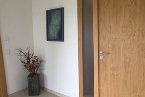 A wooden door with a metal handle, a potted plant with red flowers, and a framed abstract painting on the wall. - Holiday apartment with 1 bedroom (Breitenberg)