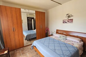 A bedroom with a bed, a wardrobe, a mirror, and a wall-mounted artwork. - Apartment Benefizio, pool and tuscan nature (Scansano)