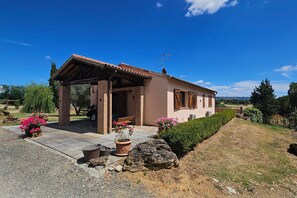 A single-story house with a covered porch, a satellite dish, and a well-maintained garden with potted plants. - Apartment Benefizio, pool and tuscan nature (Scansano)