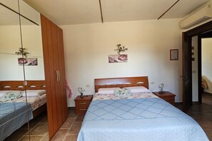 A bedroom with a bed, a wardrobe, a bedside table, and a mirror. - Apartment Benefizio, pool and tuscan nature (Scansano)