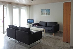 A modern living room with a sofa, a coffee table, and a television. - Holiday home with 2 bedrooms (Uhldingen - Mühlhofen)