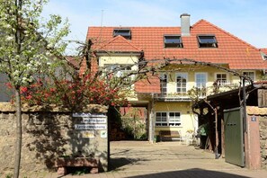 A traditional building with a red-tiled roof, a stone wall, and a sign indicating a guesthouse and restaurant. - Holiday apartment with 1 bedroom (Endingen-Königschaffhausen)