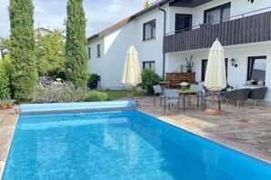A swimming pool with a patio area, outdoor furniture, and a two-story building with balconies. - Holiday apartment in Salem with swimming pool (Salem)