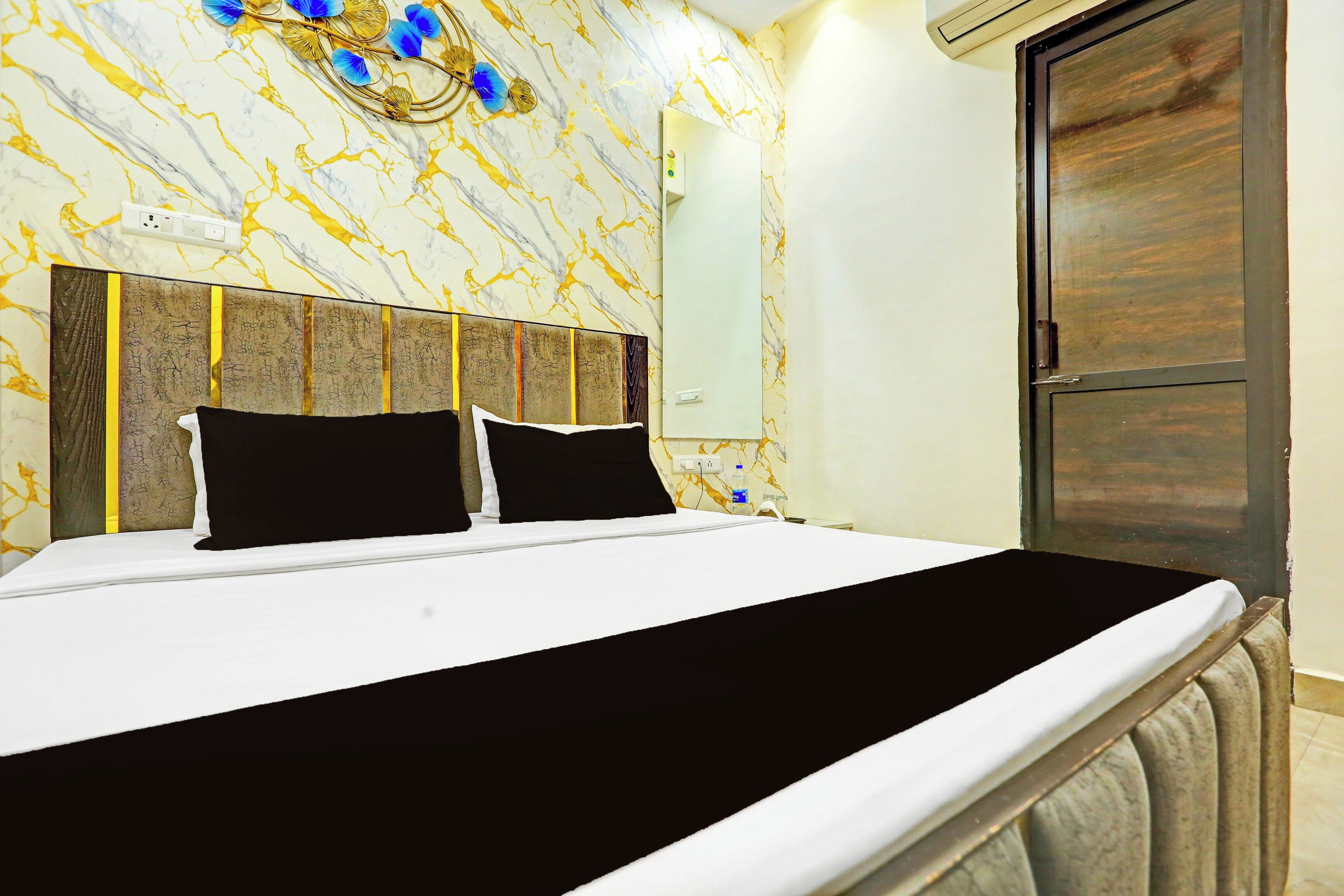 Una habitación de hotel con una cama, cabecera, aire acondicionado de pared y una puerta.