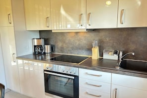 A modern kitchen with stainless steel appliances, a built-in oven, and a double sink. - Holiday home with 2 bedrooms (Büsumer-Deichhausen)