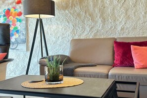 A living room with a sofa, a floor lamp, a coffee table with a glass vase, and a wall with a textured pattern. - Holiday home with 2 bedrooms (Büsumer-Deichhausen)