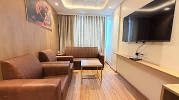 Una sala de estar moderna con sofás de cuero, una mesa de centro de madera, un televisor de pantalla plana montado en la pared y un ventilador de techo.