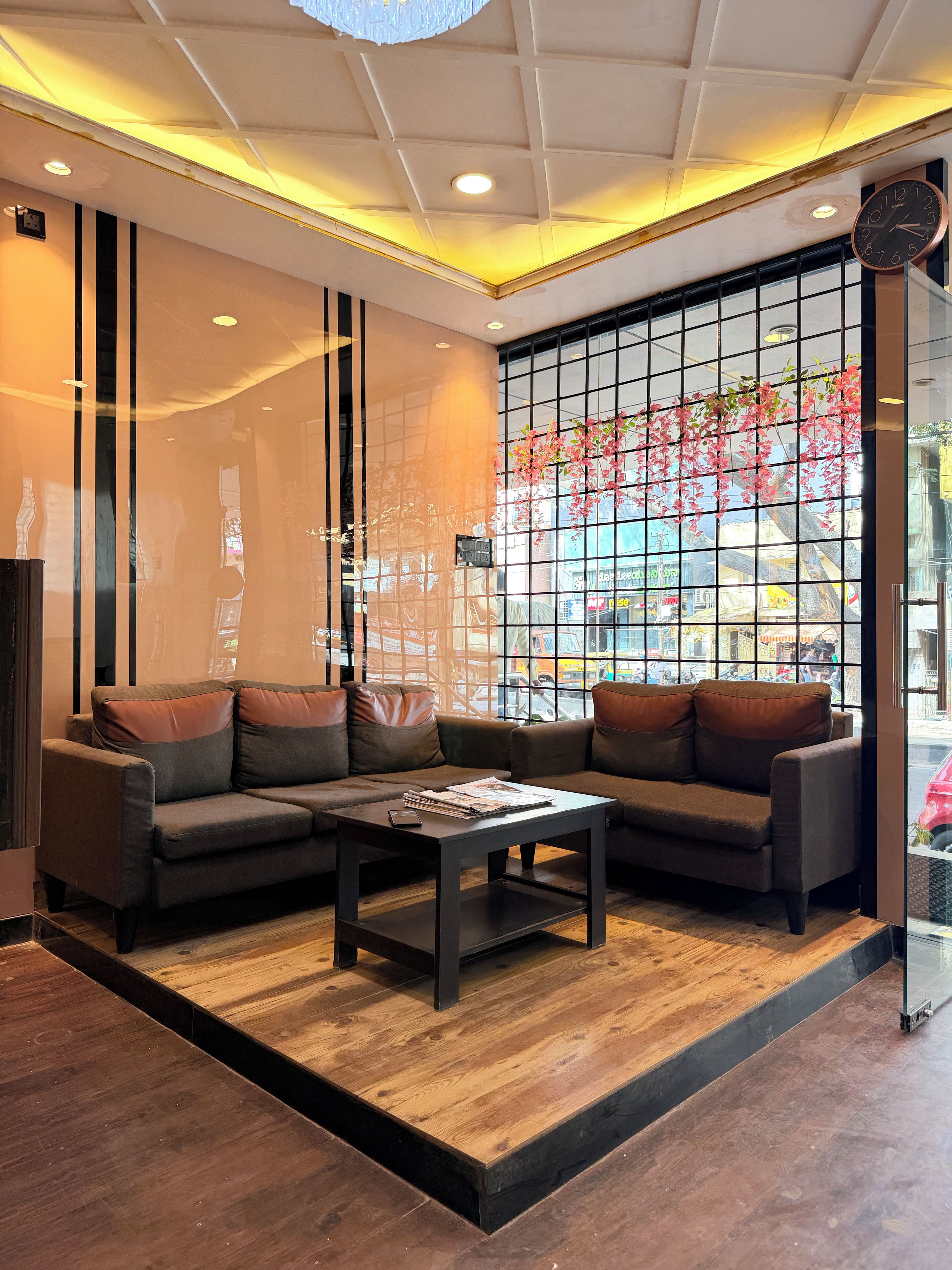 A modern interior with a sectional sofa, a coffee table, and a large window with a view of the street.