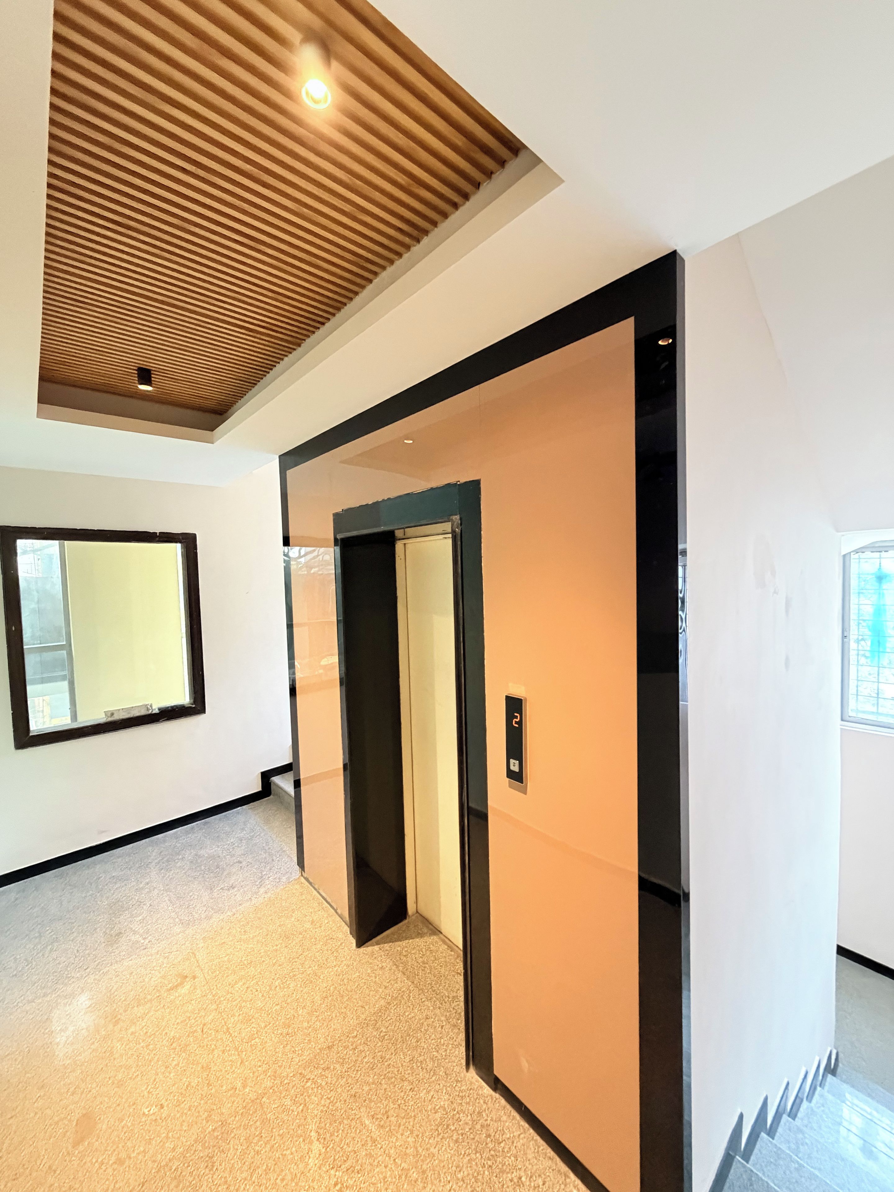 A modern interior with a wooden ceiling, a large window, and a door with a number indicating a room or floor.