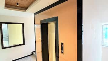 Un interior moderno con techo de madera, un ventanal grande y una puerta con un número que indica una habitación o piso.