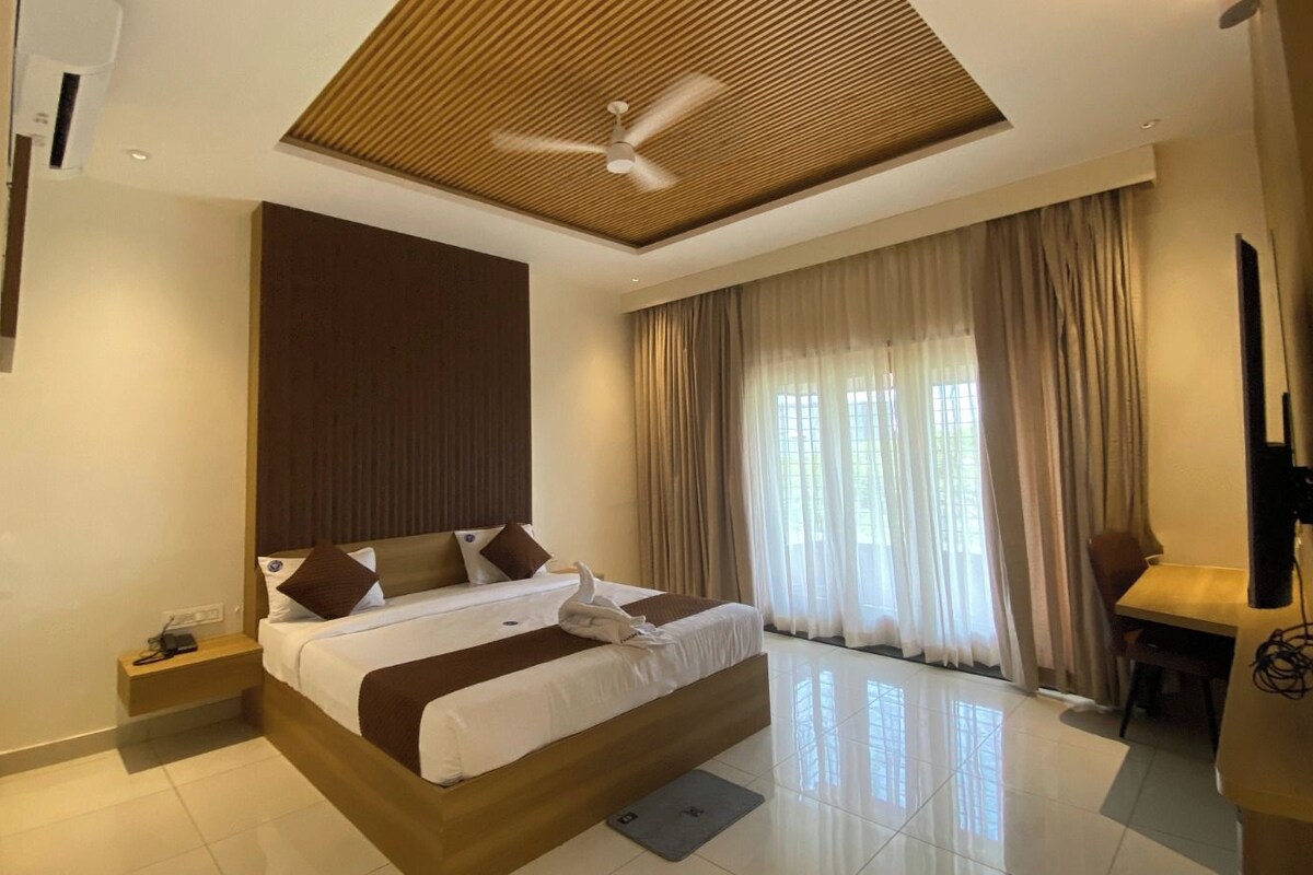 A hotel room with a large bed, a ceiling fan, a desk, and a TV.