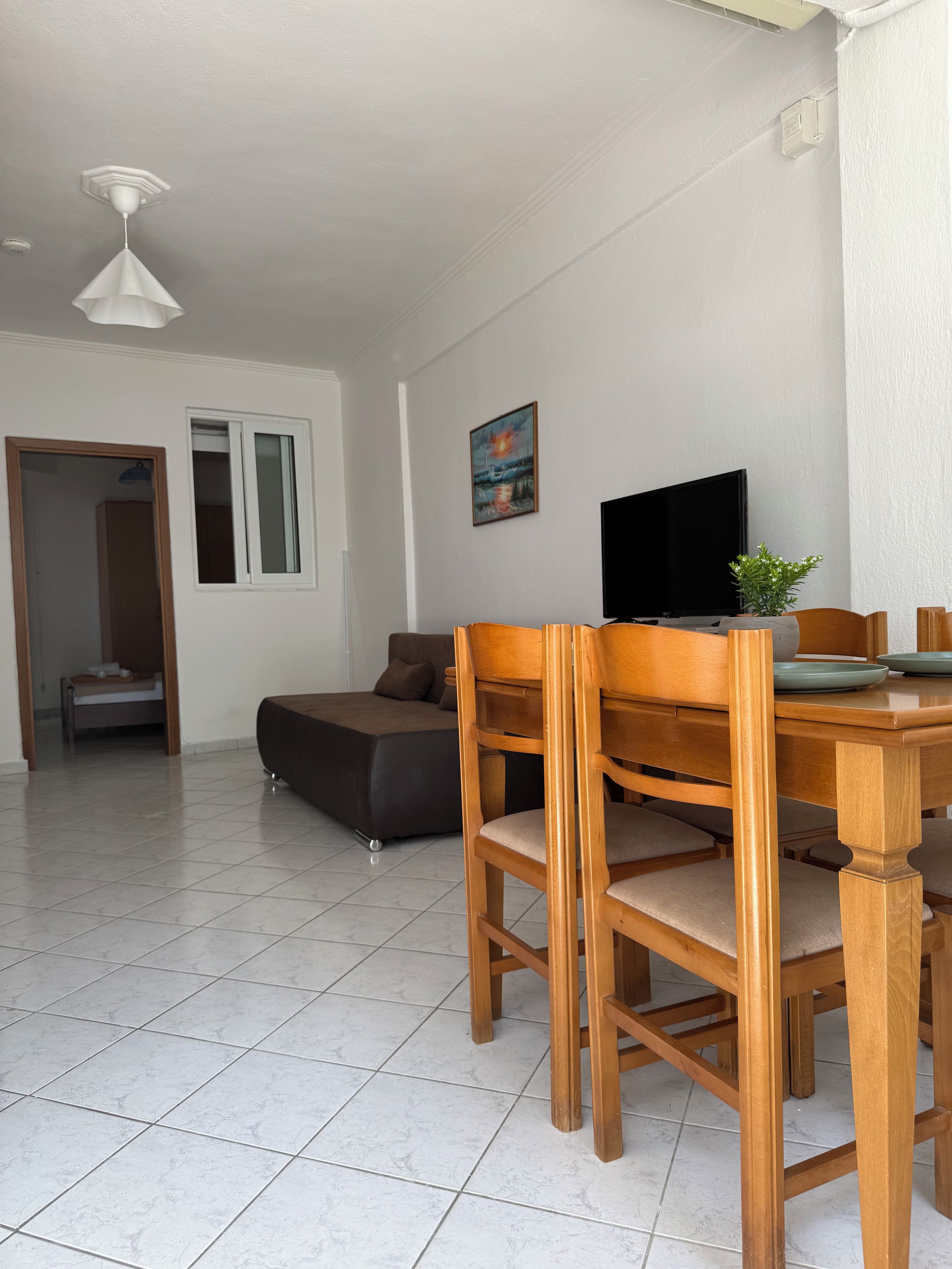 Uma sala de estar moderna com área de jantar, televisão de tela plana e um quadro na parede.
