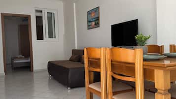 Uma sala de estar moderna com área de jantar, televisão de tela plana e um quadro na parede.