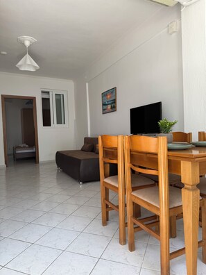 Una sala moderna con comedor, televisor de pantalla plana y un cuadro en la pared.