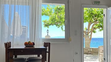 Quarto com mesa de jantar, cadeiras, janela com vista para o mar e luminária pendente.