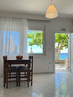 Una habitación con una mesa de comedor, sillas, un ventanal con vista al mar y una lámpara colgante.