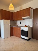 A kitchen with wooden cabinets, a white refrigerator, a stove, and a hanging light fixture.