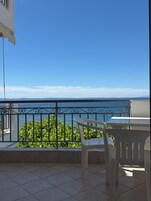 Un balcón con vistas al mar, una mesa y sillas.