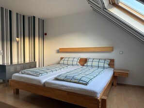Et soveværelse med en træseng, et natbord, en indbygget bænk og et skråt loft med ovenlys.