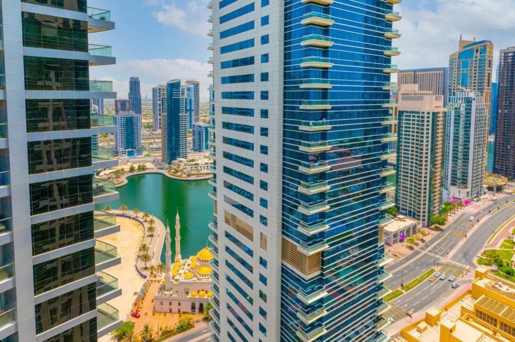 A high-rise building with a modern design, surrounded by other tall buildings and a body of water.