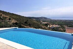 A swimming pool with a view of a hilly landscape and distant buildings. - Holiday apartment in Roses with swimming pool (Roses)