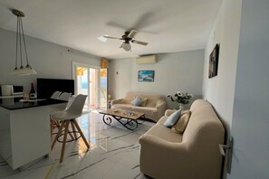 A modern living room with a sofa, a coffee table, and a TV. - Holiday apartment in Roses with swimming pool (Roses)