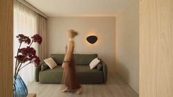 Ein Zimmer mit einem grünen Sofa, einer Vase mit roten Blumen und einer Wandleuchte.
