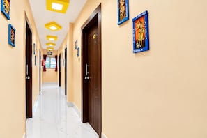 A hotel hallway with marble flooring, wooden doors, and framed artwork on the walls.
