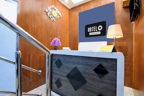 A hotel reception desk with a 'HOTEL' sign, a decorative clock, and a lamp.