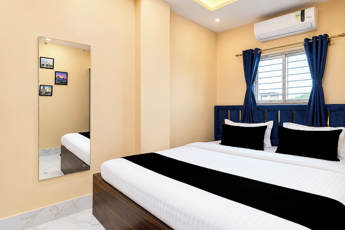 A bedroom with a bed, a mirror, an air conditioner, and a window with curtains.