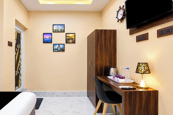Ein Hotelzimmer mit Bett, Schreibtisch, Sessel, Fernseher und Wandbildern.
