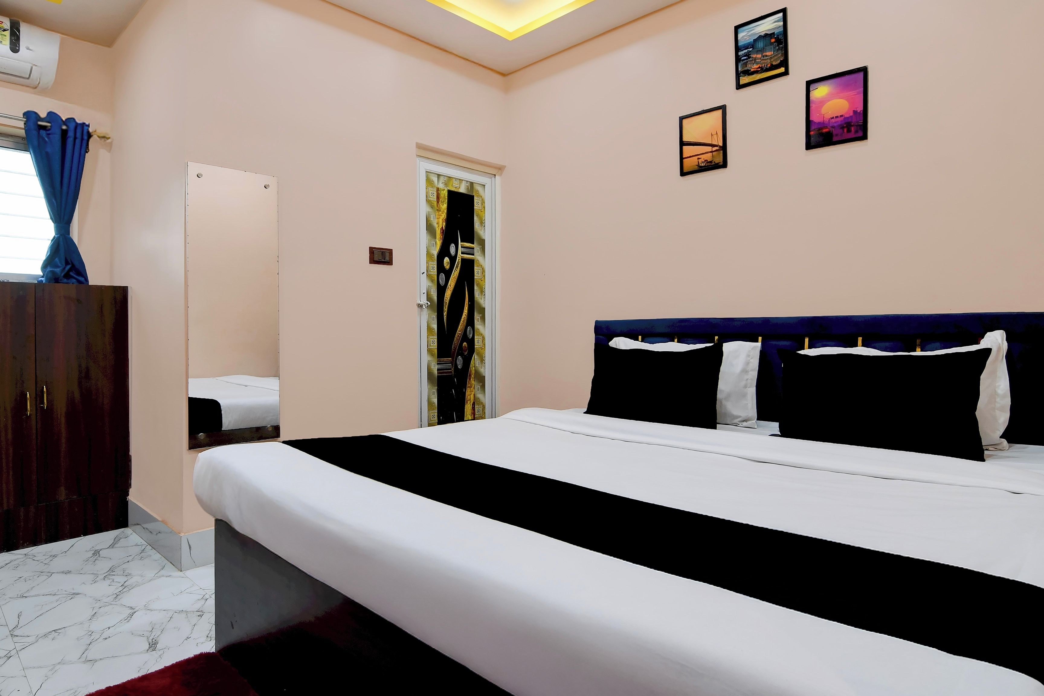 Habitación de hotel con cama, armario, puerta con panel decorativo y cuadros colgados en la pared.