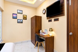 A hotel room with a bed, a desk with a chair, a television, and a wardrobe.