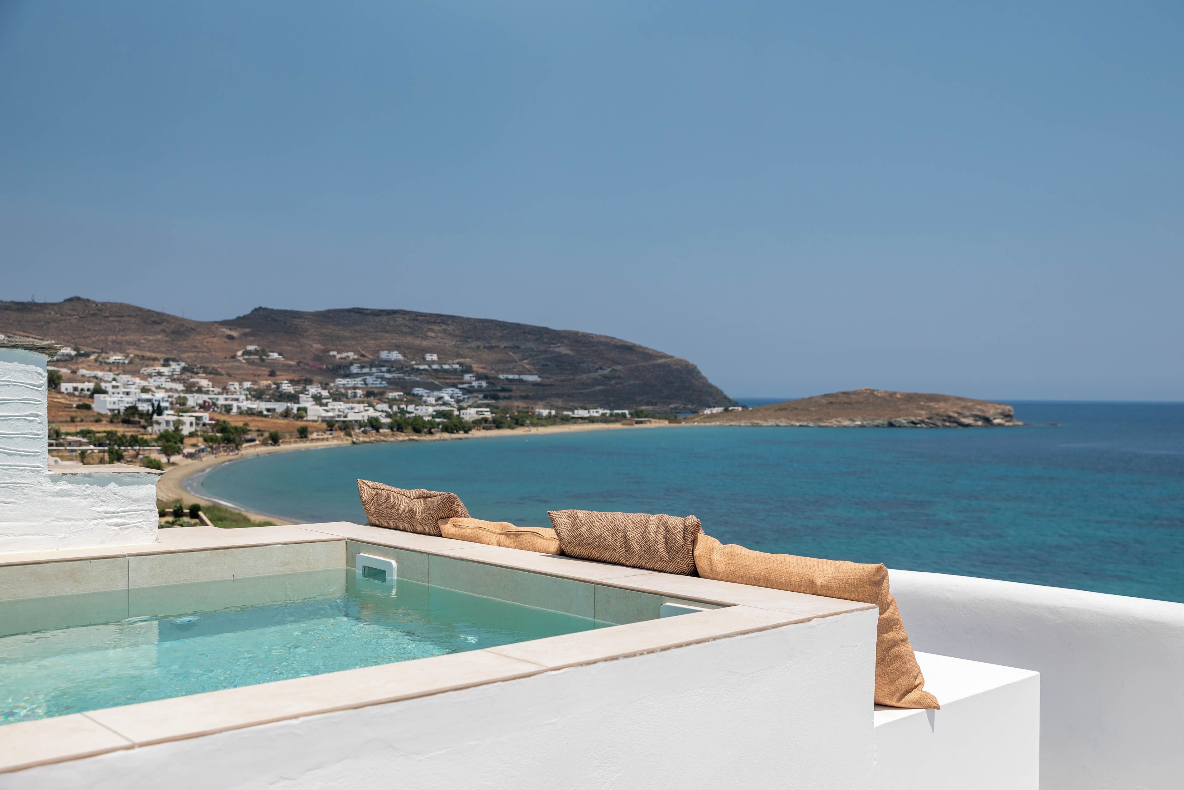 A pool with a view of a beach and a hillside town.
