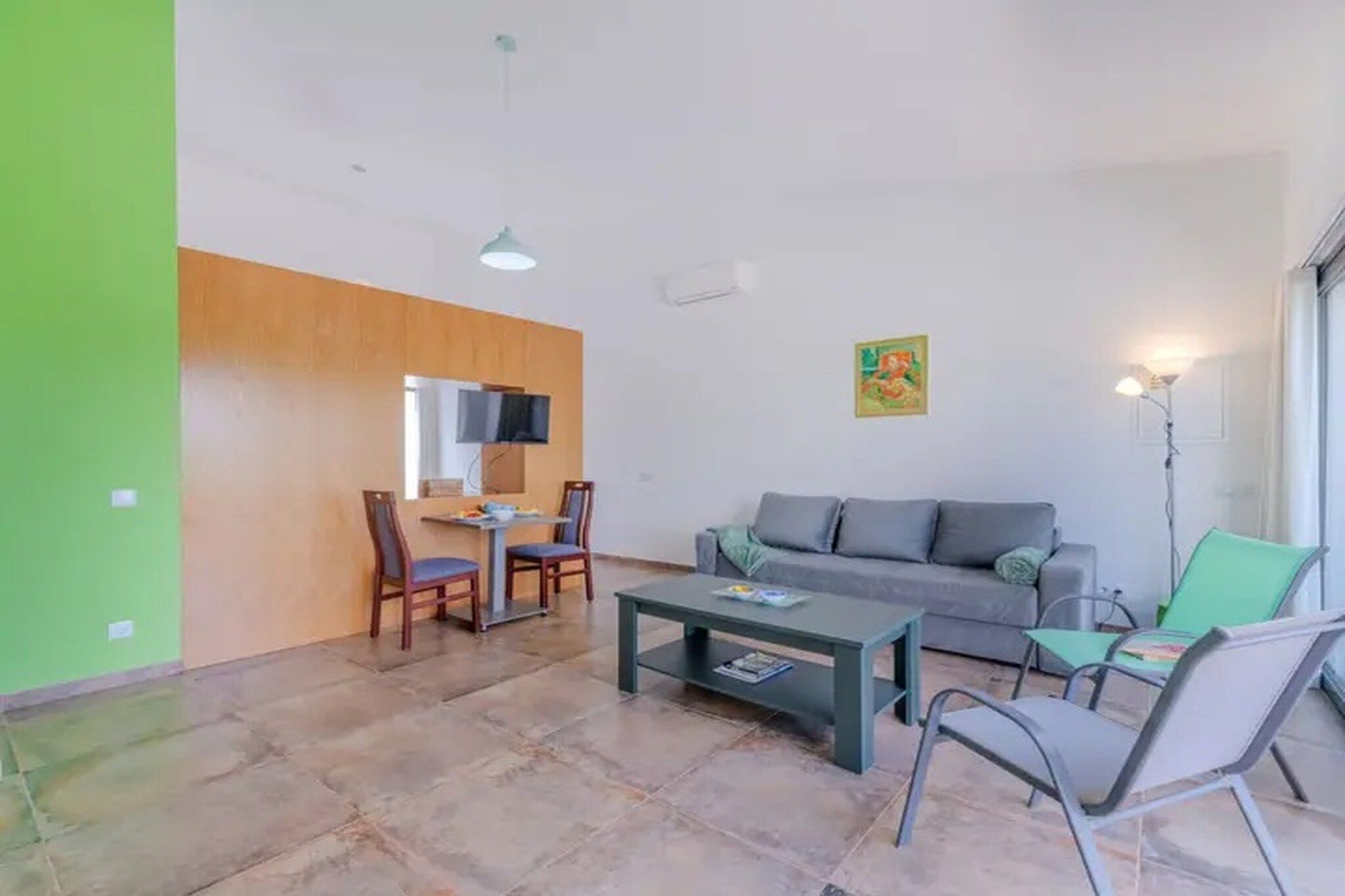 A living room with a sofa, chairs, a coffee table, and a television.
