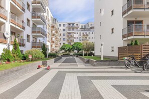 A residential building with multiple balconies, a paved courtyard, and a bicycle parked outside. - Lumina Comfort 3-room Apt w/ Parking I Balcony (Warszawa)