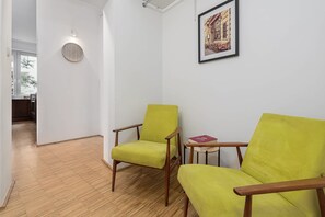 A room with two yellow chairs, a round wall clock, and a framed picture on the wall. - Lumina Comfy 2BR Apart near the Center of Warsaw (Warszawa)