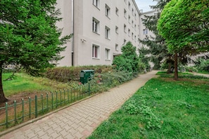 A pathway leading to a building with multiple windows, surrounded by greenery and a fence. - Lumina Comfy 2BR Apart near the Center of Warsaw (Warszawa)
