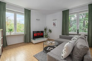 A modern living room with a grey sofa, a coffee table, a flat-screen TV displaying 'NETFLIX,' and a framed picture on the wall. - Lumina Comfy 2BR Apart near the Center of Warsaw (Warszawa)