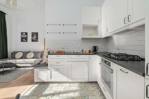 A compact kitchen with white cabinets, a gas stove, and a sink. - Lumina 2-room Apart in the Center I cozy Balcony (Warszawa)