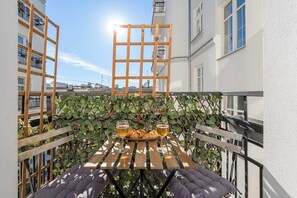 A wooden table with a glass of beer and croissants on a balcony with a lattice fence and ivy. - Lumina 2-room Apart in the Center I cozy Balcony (Warszawa)