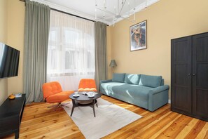 A living room with a sofa, armchair, coffee table, and a television. - Poznan Dabrowskiego 49 Spacious Apartment Balcony (Poznań)