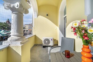 A balcony with a white air conditioning unit, a wicker chair, a table, and a vase with flowers. - Poznan Dabrowskiego 49 Spacious Apartment Balcony (Poznań)