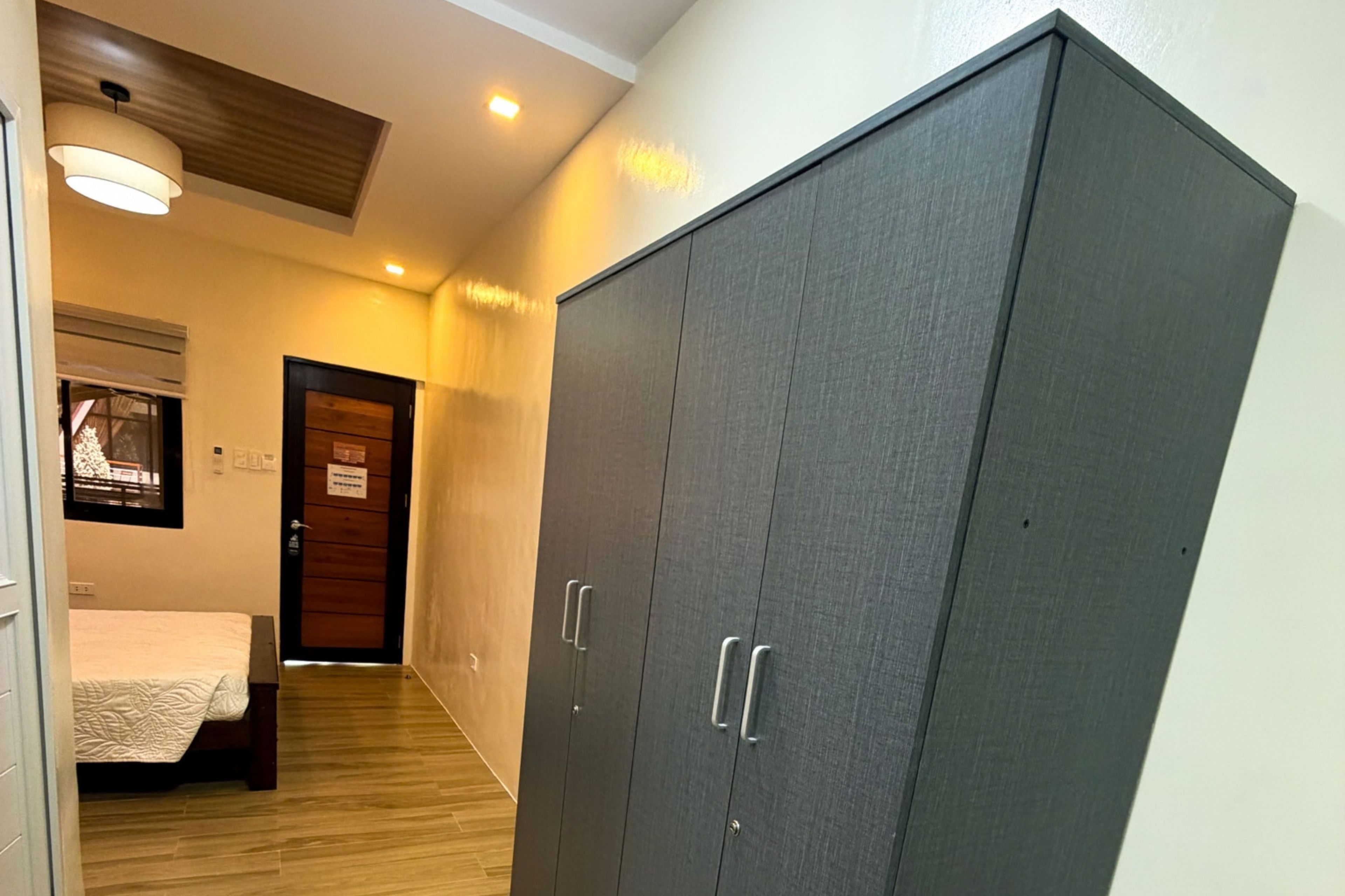 Un pasillo con una cama, un armario y una puerta con un letrero.