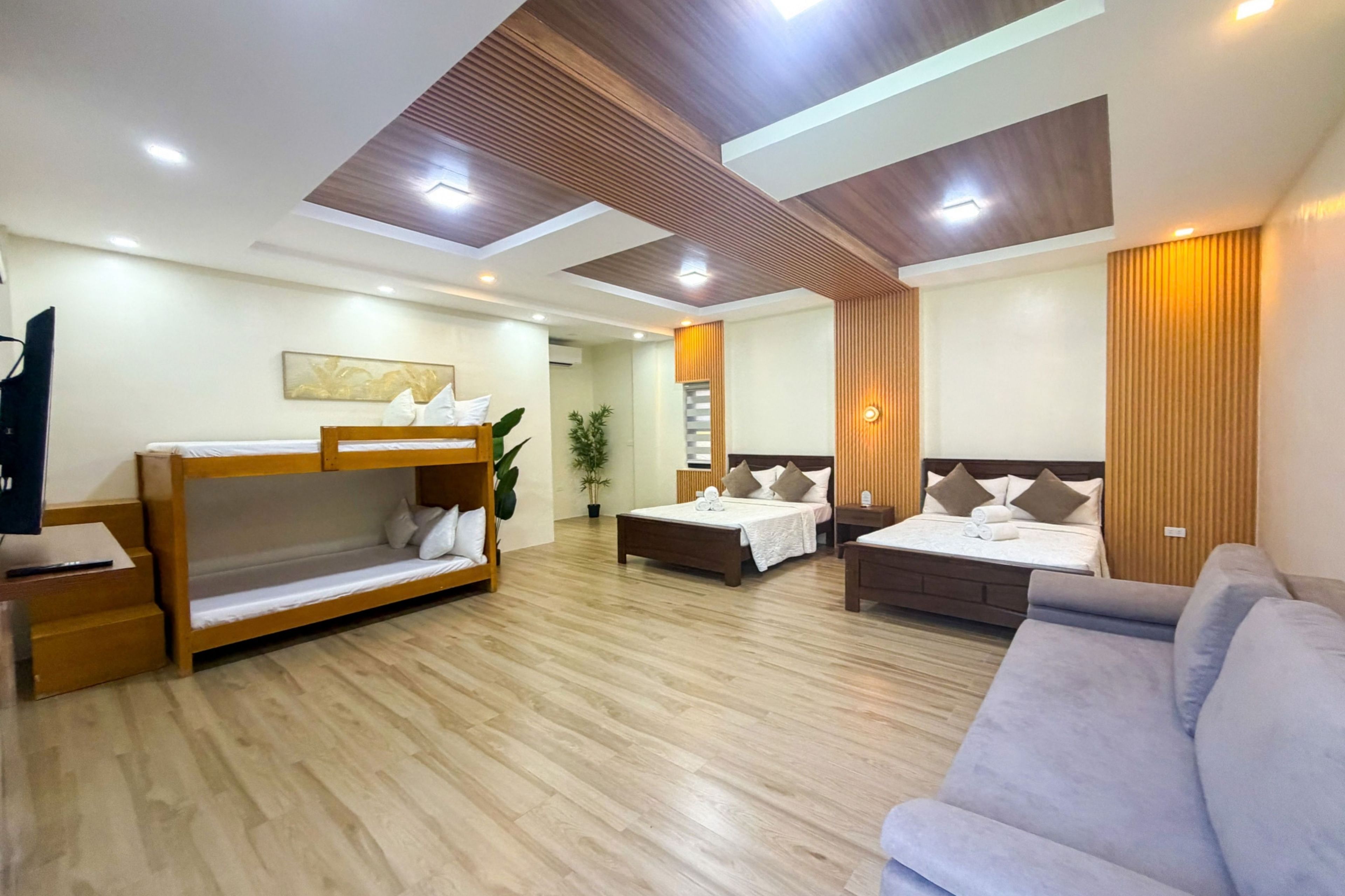 Habitación de hotel con literas, sofá, escritorio y cama con cabecera.
