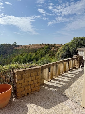 A terrace with a stone wall and tiled flooring, overlooking a hilly landscape with greenery. - Secluded Mountainside Retreat w/ Pool, Sauna + Gym (Caldas de Monchique)